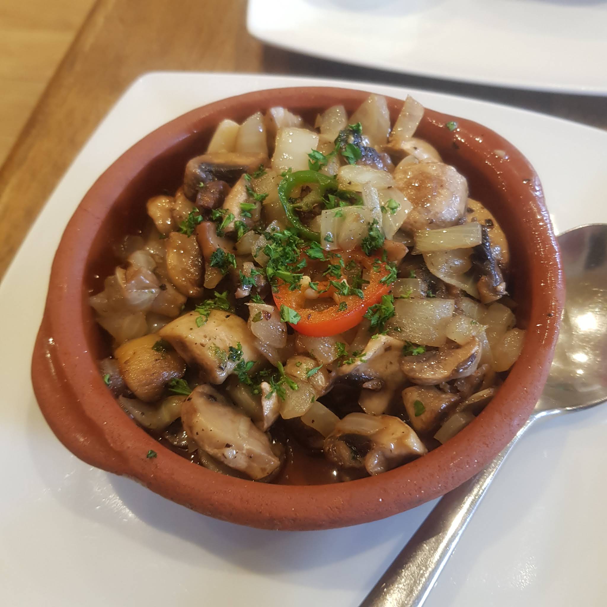 A complete terracotta bowl of mushrooms and vegetables at Mi Casa Su Casa
